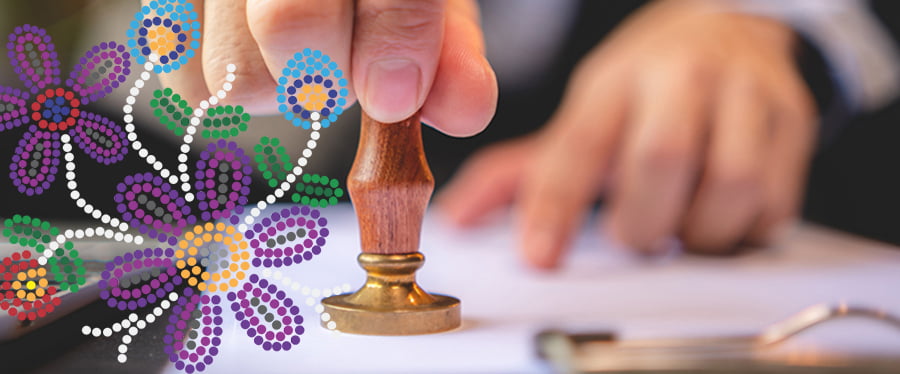 Someone's hand pressing a stamp against a piece of paper next to Metis style bead motif