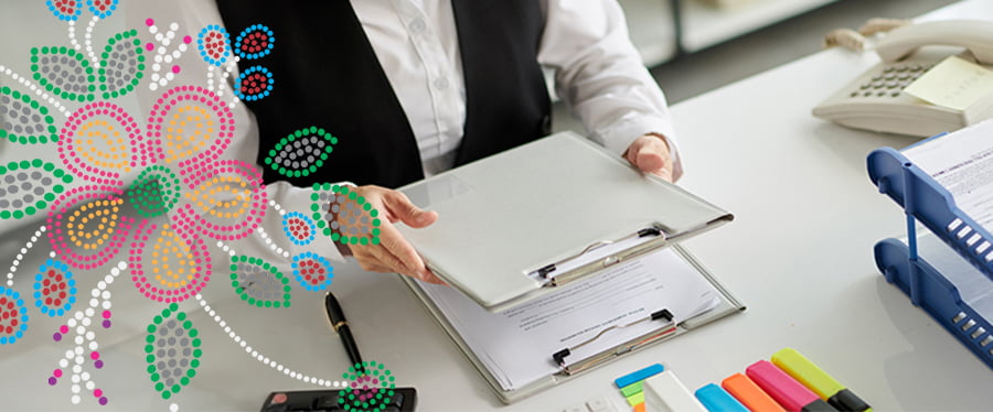 Office worker holding a clipboard on a desk with a phone and office supplies with a Metis inspired bead design overlay