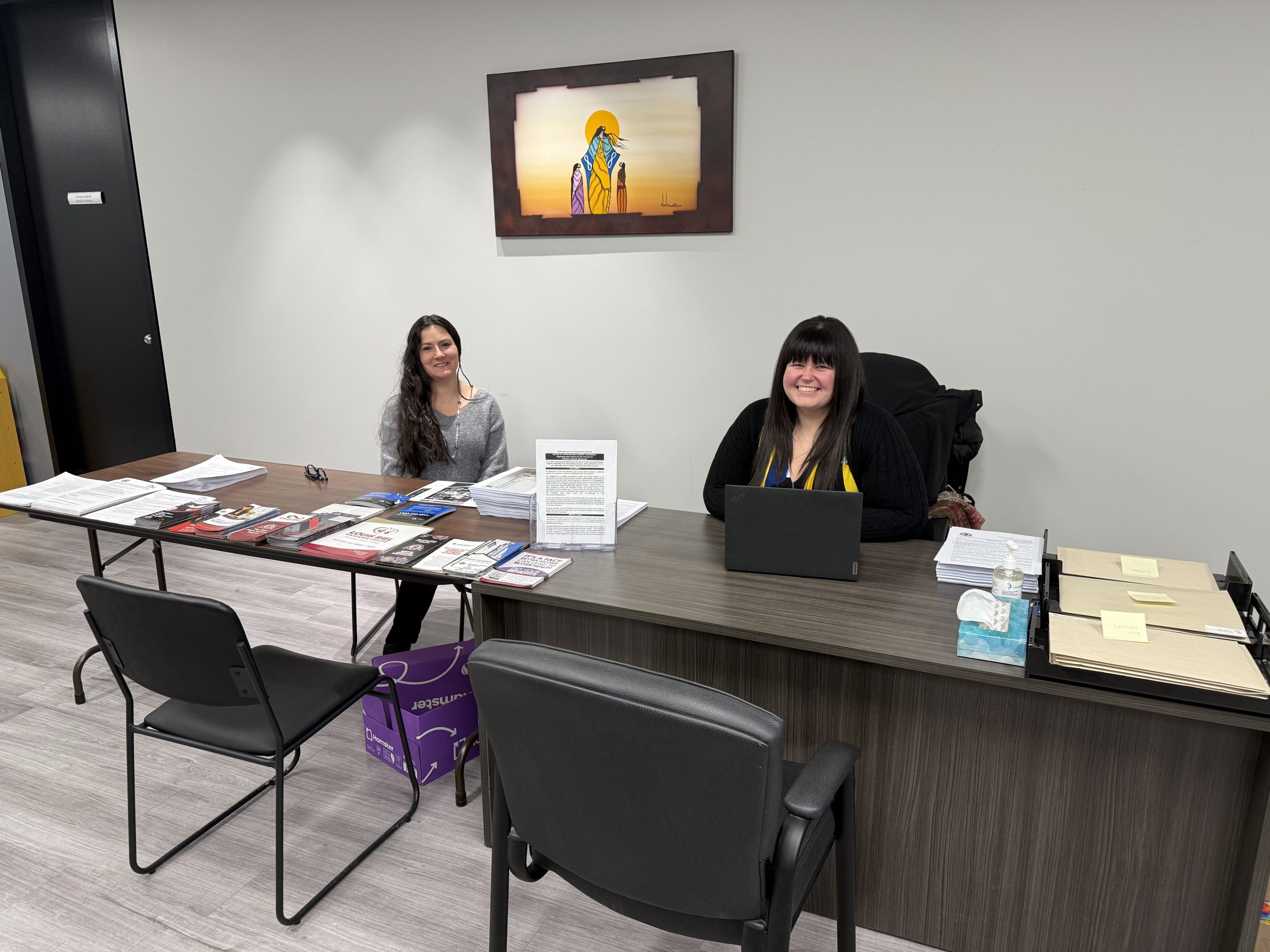 Two smiling people welcome visitors from behind an information desk